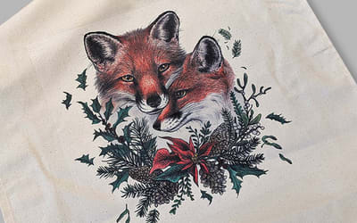 A white tea towel with an illustration of two foxes on it
